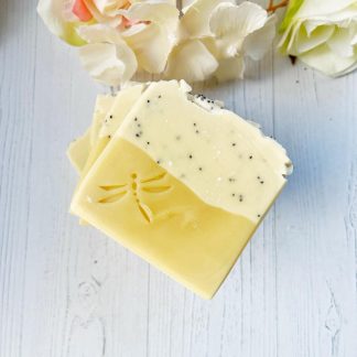 Savon artisanal fait main au citron et aux graines de pavot, enrichi en huiles essentielles, avec une texture exfoliante naturelle et une couleur jaune éclatante. Présenté sur un fond neutre avec une ambiance fraîche et naturelle